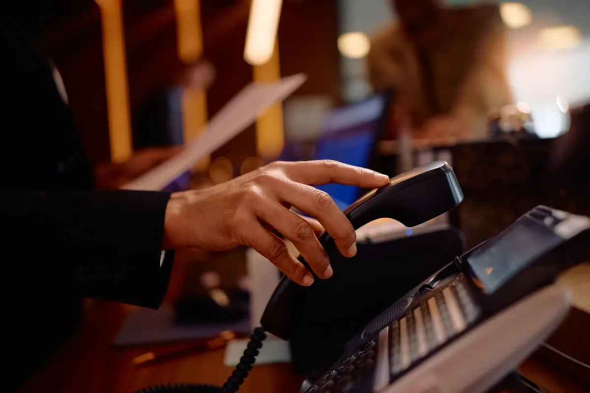 Hand greift zum IP-Tischtelefon am Empfang