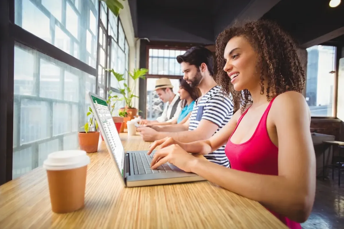 Team arbeitet produktiv mit Microsoft 365 — Office-Icons fliegen aus dem Laptop