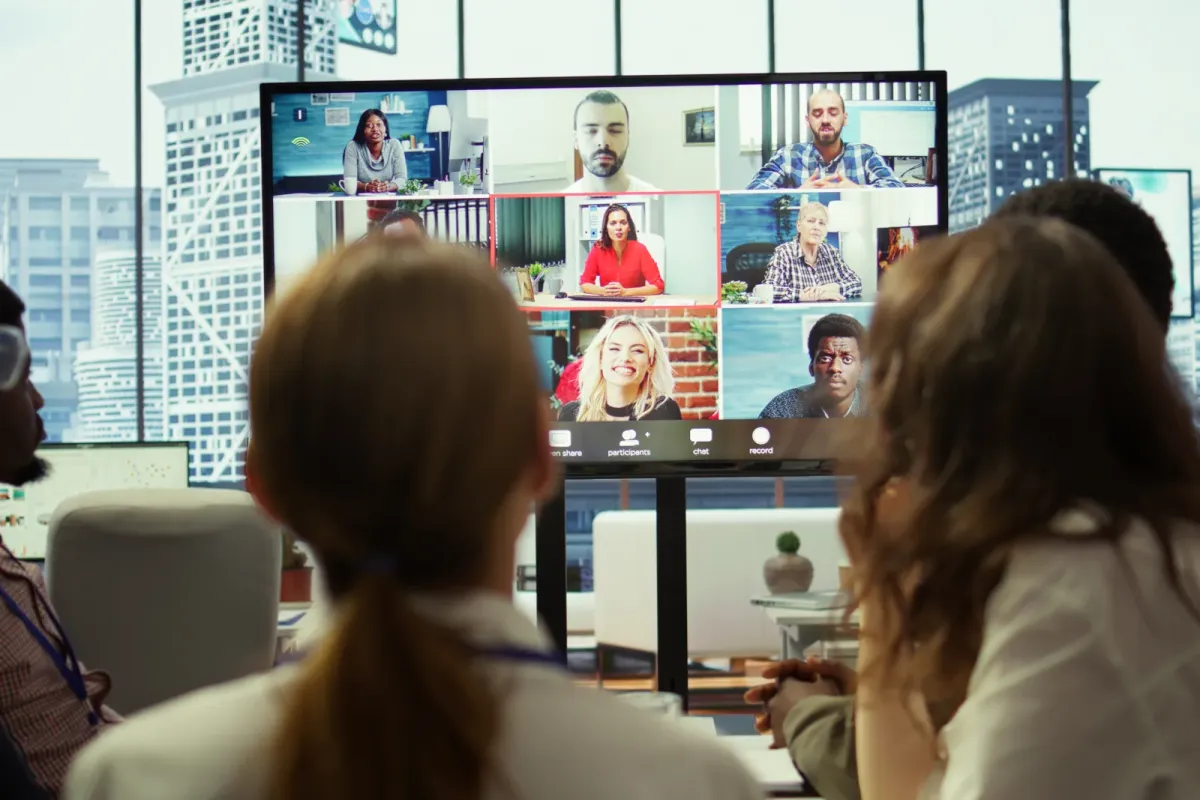 Hybrides Team-Meeting — Büro-Mitarbeiter und Remote-Teilnehmer