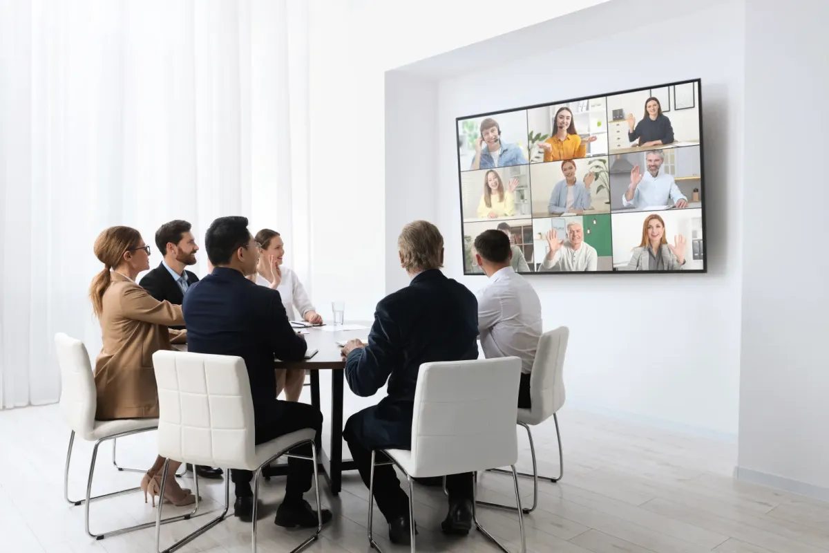 Geschäftsleute im Konferenzraum mit großem Videokonferenz-Display